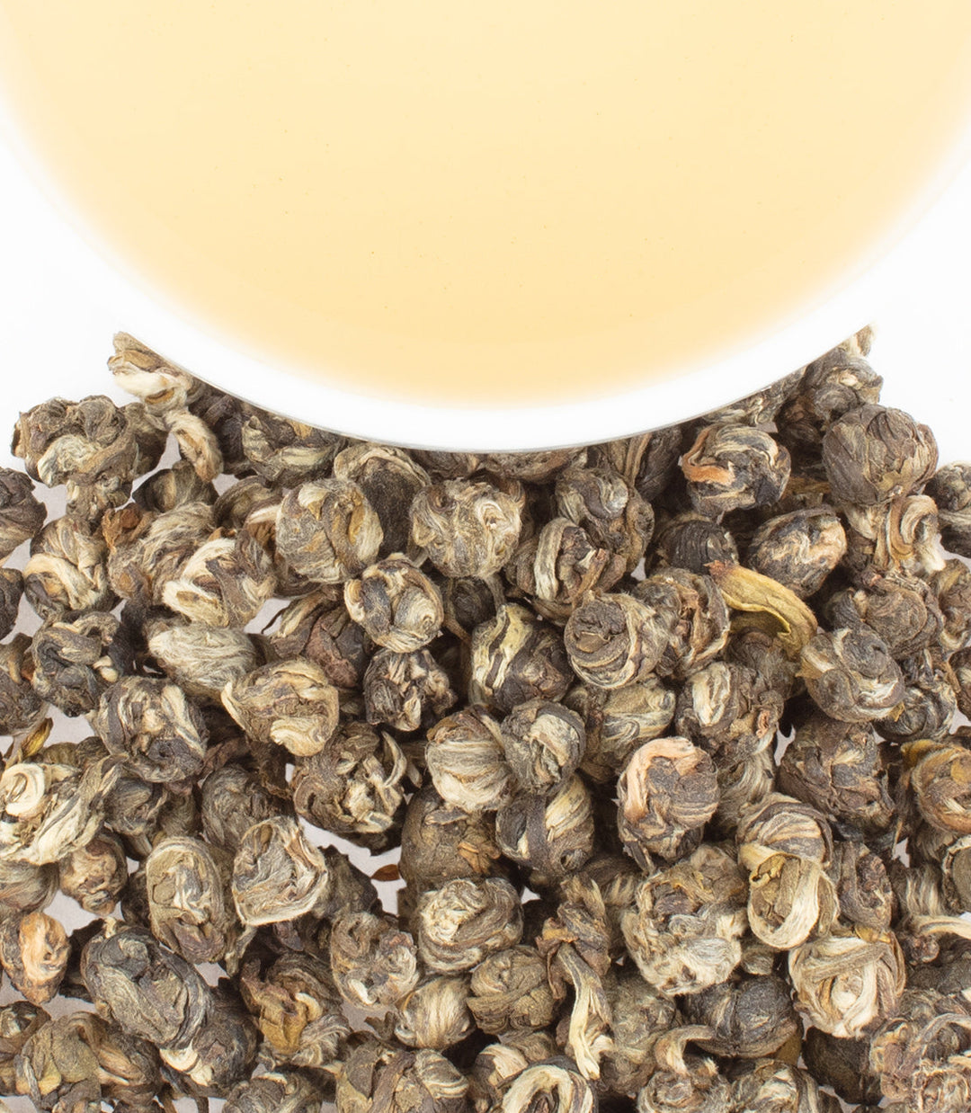 Close-up of dried tea leaves with a blurred white container in the background.