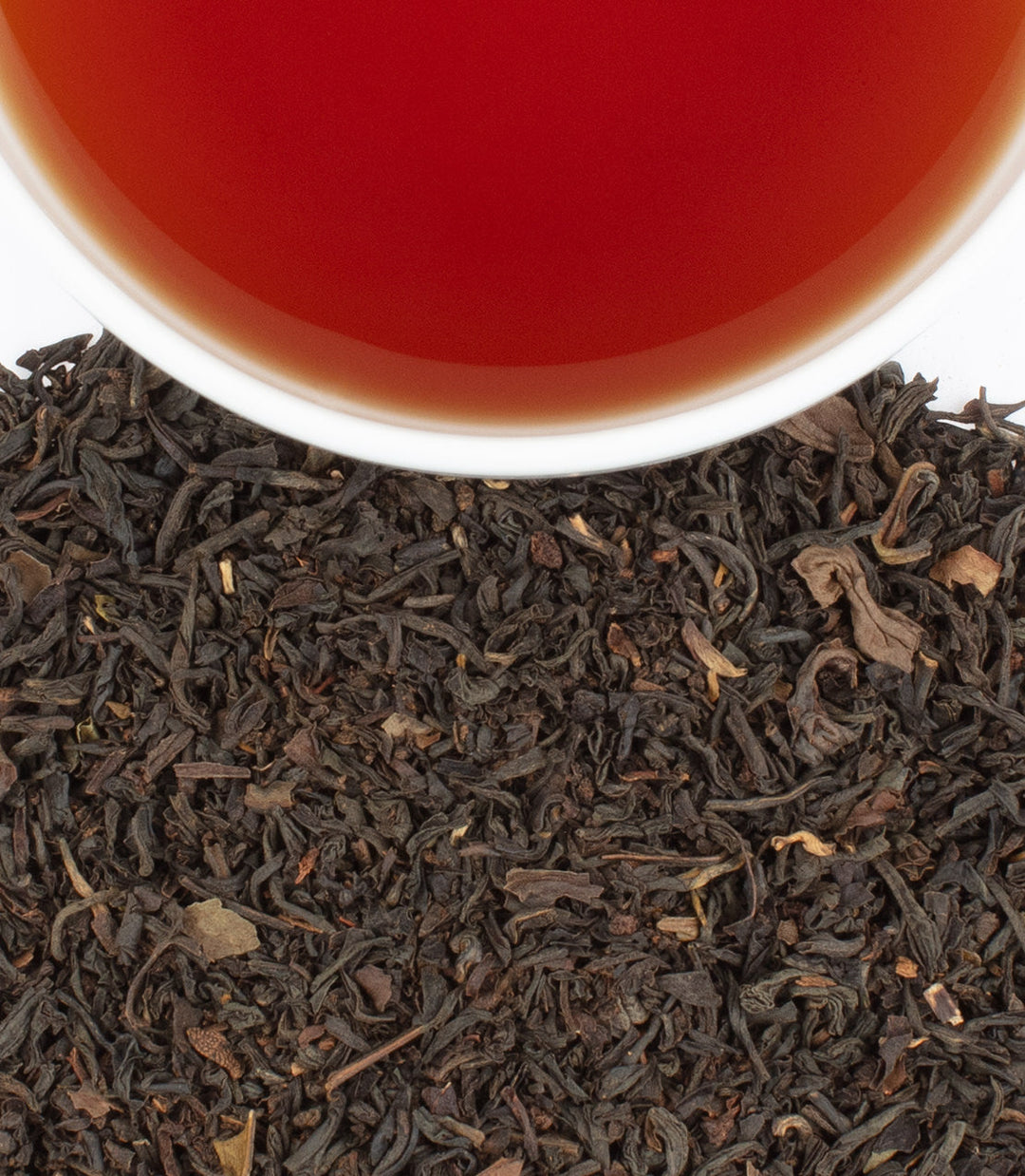 Close-up of tea leaves with a cup of tea in the background.