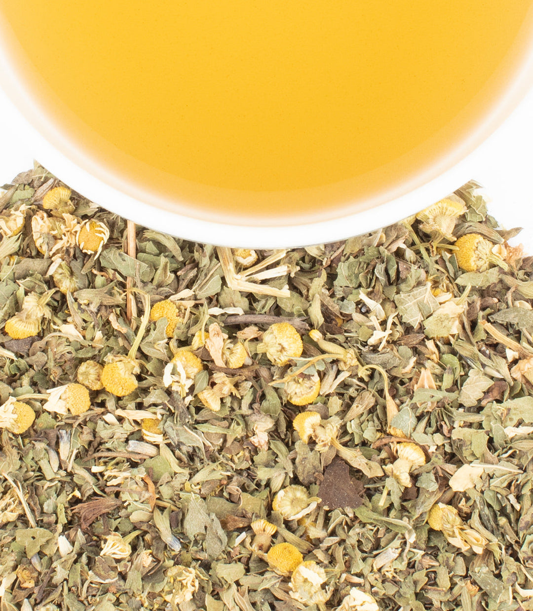 Tea leaves with a cup of tea in the background