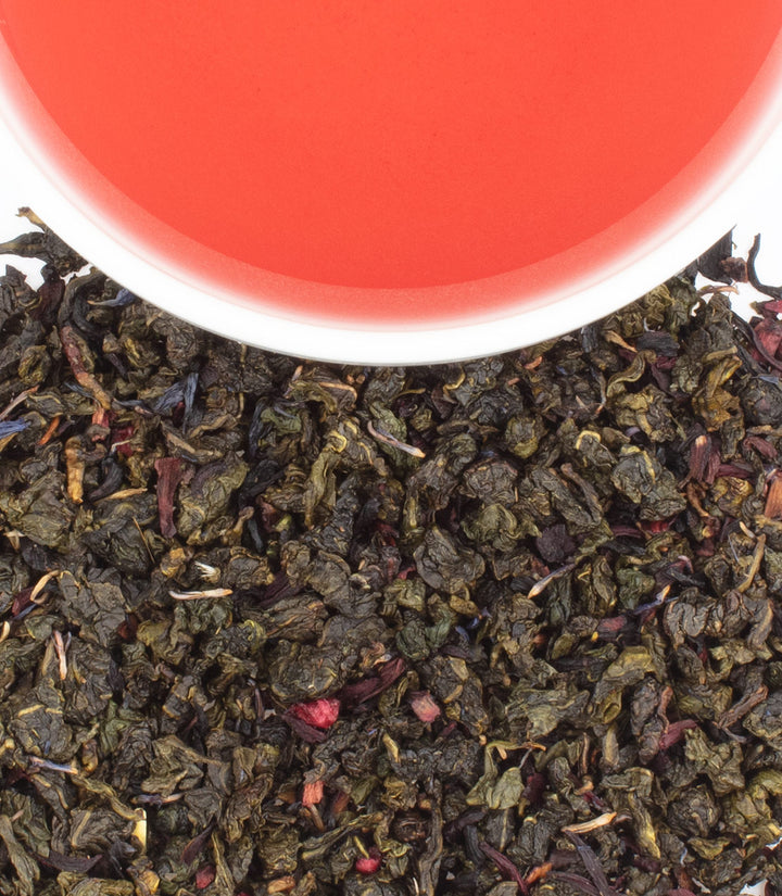 Tea leaves with a cup of red tea in the background.