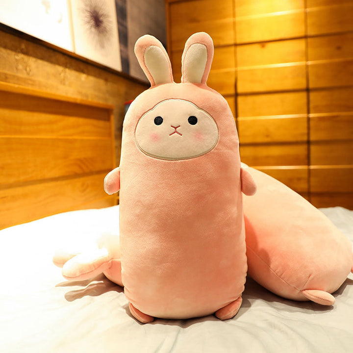 Plush toy shaped like a rabbit on a bed with wooden paneling in the background.