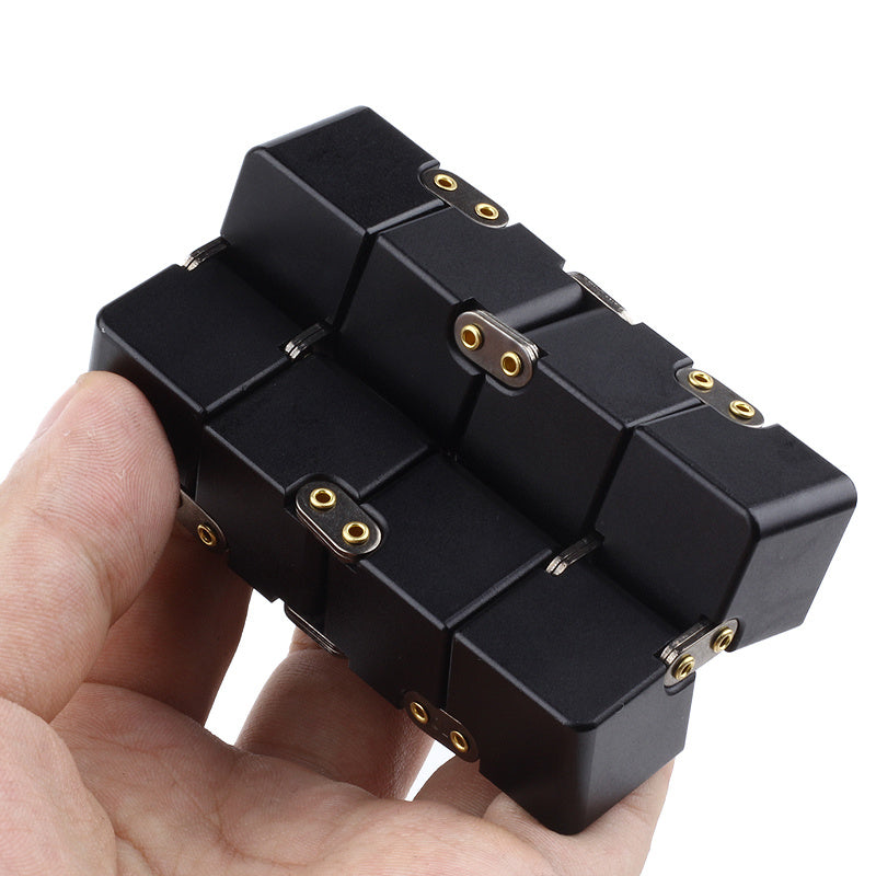 Black modular cube puzzle held in a hand against a white background.