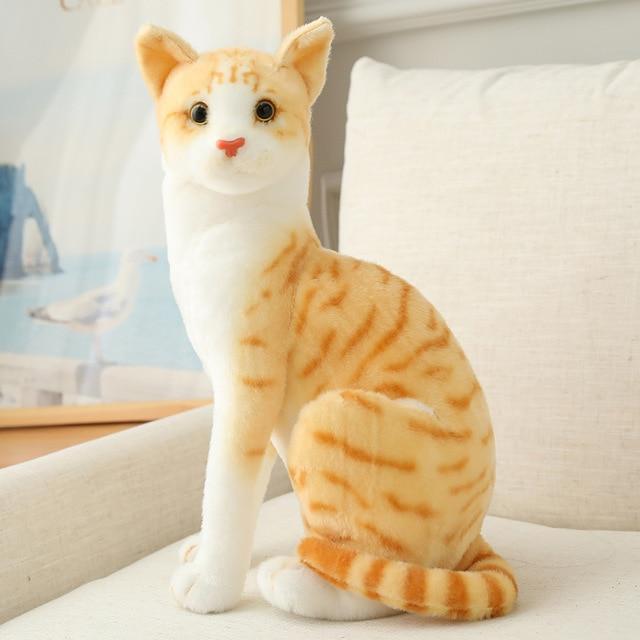 Plush toy cat with orange and white stripes on a light background.