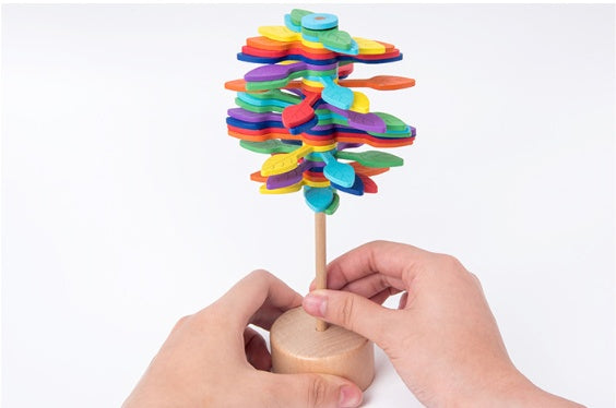 Colorful wooden toy with spinning disks held by a hand on a white background.