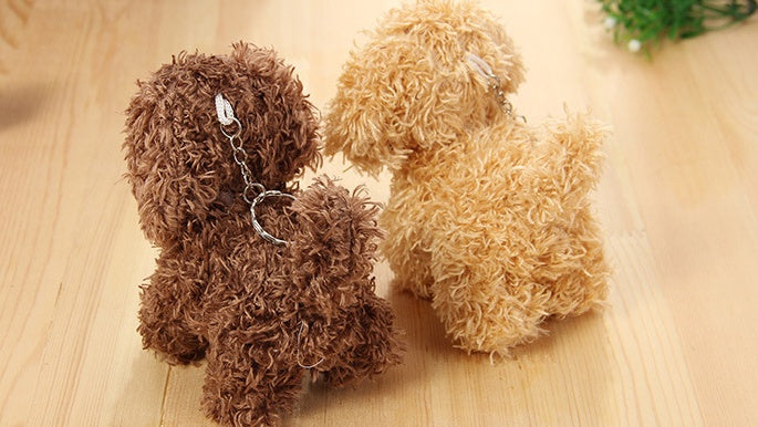 Two fluffy dog-shaped keychains on a wooden surface.