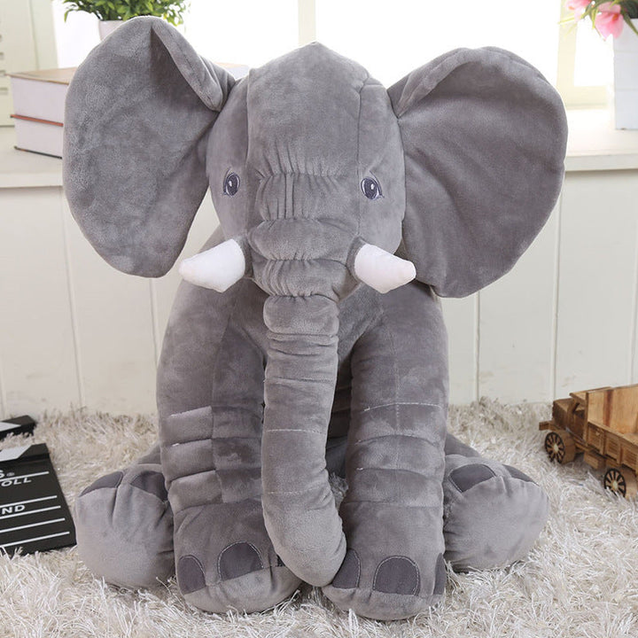 Gray plush elephant toy on a soft surface with a light background.