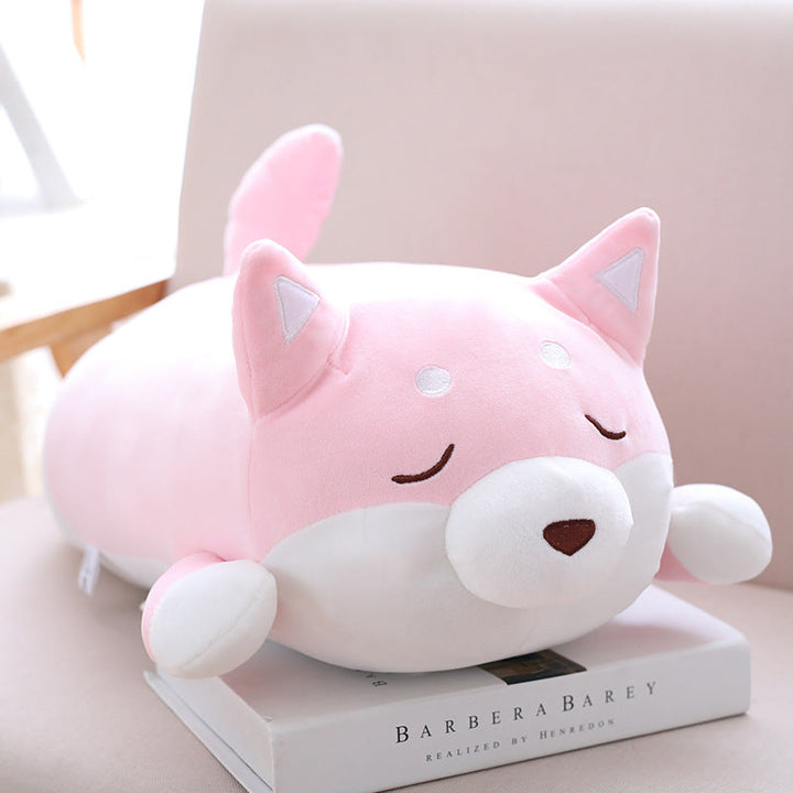 Pink and white plush toy resembling a cat on top of a book with a blurred background.