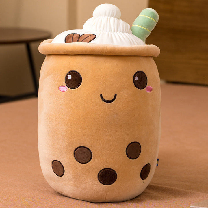 Plush toy shaped like a bubble tea cup with a smiling face on a brown surface.