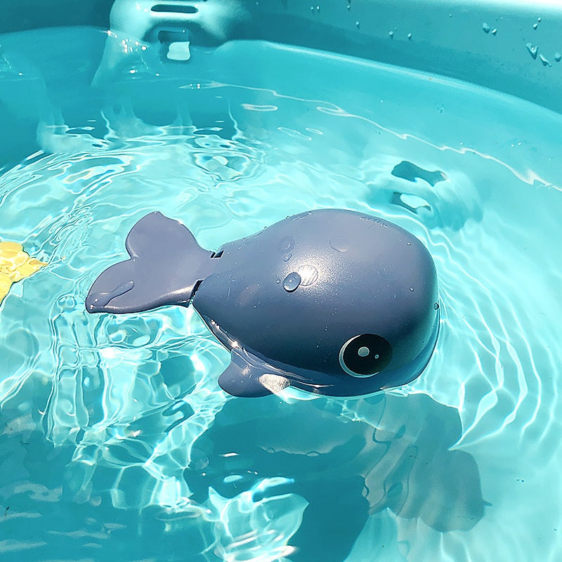 Toy whale floating in clear blue water.