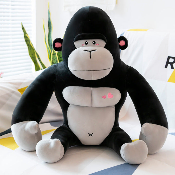 Plush monkey toy with black fur, white face, and pink heart designs on a light background.