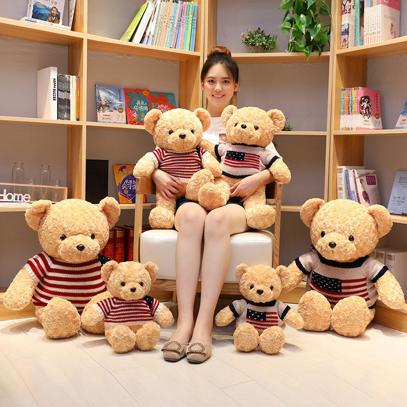 Woman sitting on a chair surrounded by teddy bears wearing striped shirts in a room with bookshelves.