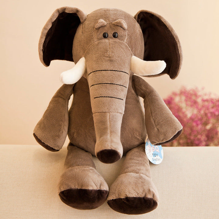 Plush elephant toy with a visible brand tag on a beige surface.