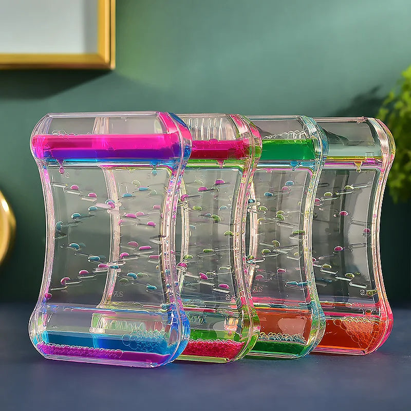 Colorful sand timers on a reflective surface with a green wall background.