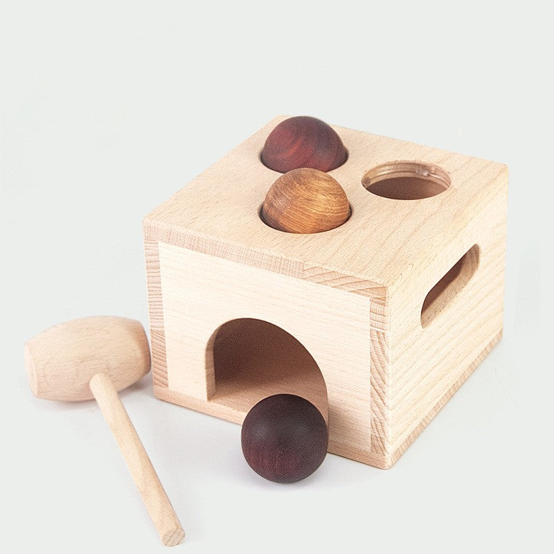 Wooden toy with compartments and a mallet on a light background.