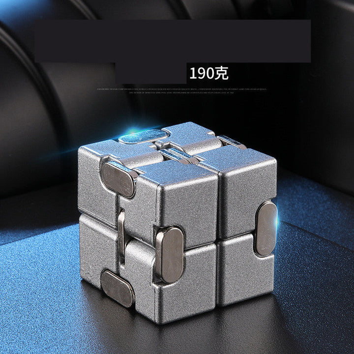 Metallic fidget cube on a dark surface with blue glowing effect.