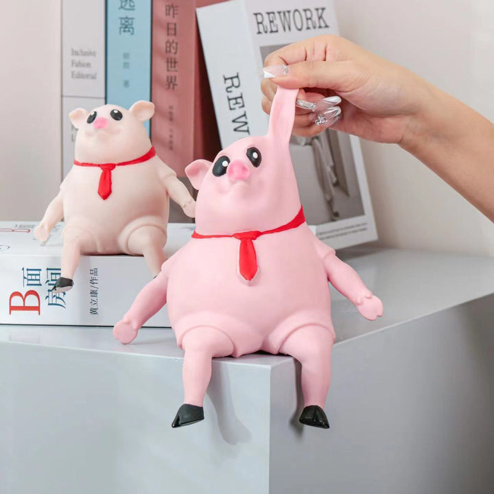 Pink plush pig toy with a red bow tie held by a hand on a shelf.