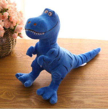 Blue dinosaur plush toy on a wooden surface with flowers in the background.