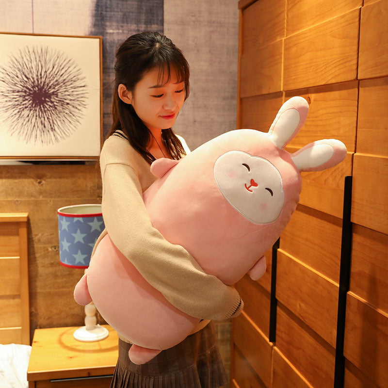 Woman holding a large pink plush toy in a room with wooden walls and decor.