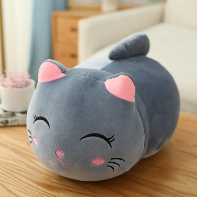 Gray cat-shaped plush toy on a wooden surface with a blurred indoor background.
