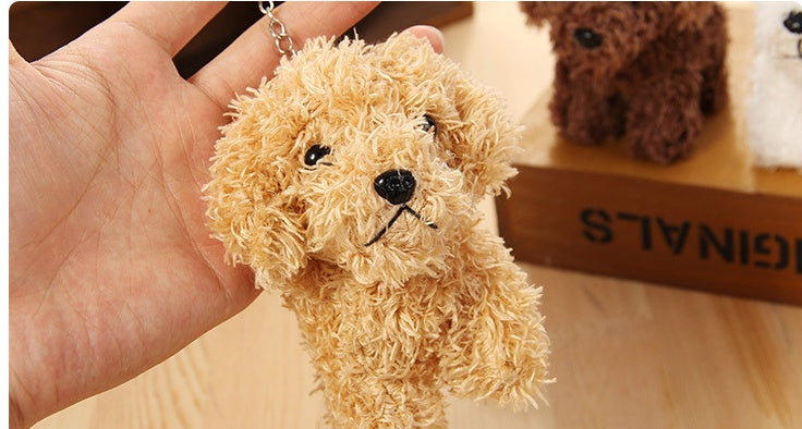 Small plush dog toy held in a hand with a wooden surface and box in the background.