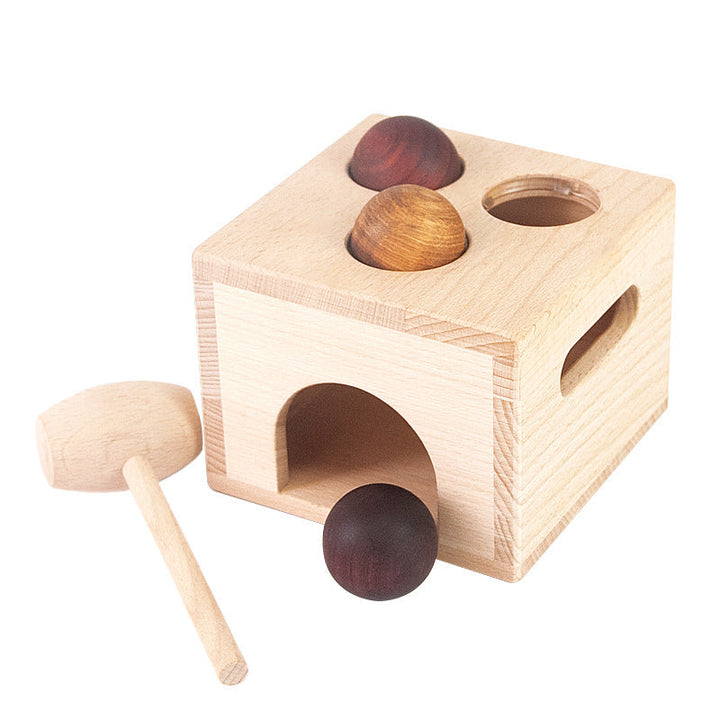 Wooden shape sorting toy with three wooden balls and a mallet on a white background.