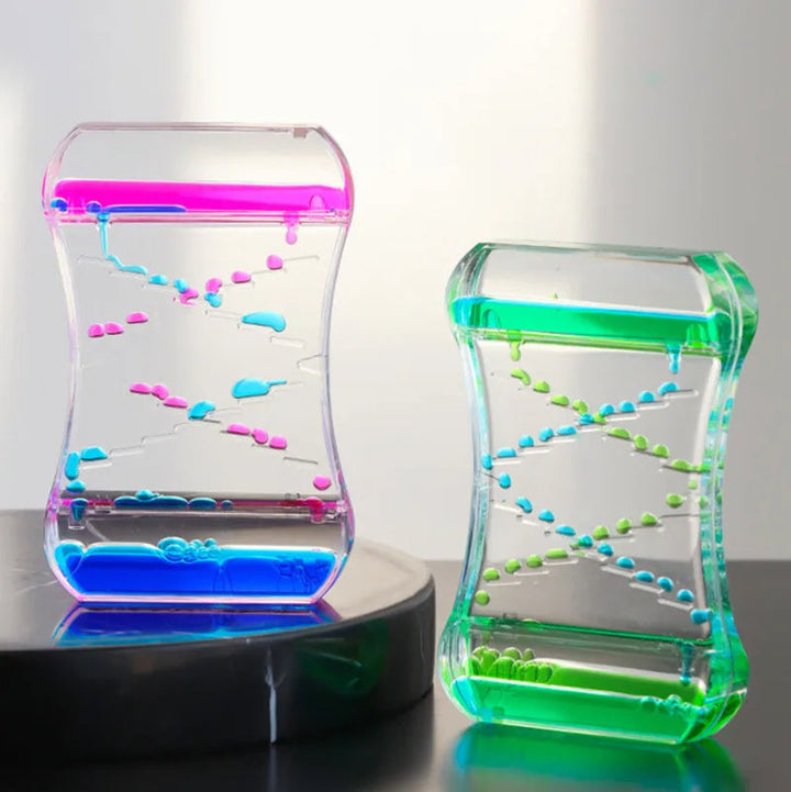 Two colorful containers with liquid and small beads on a reflective surface.