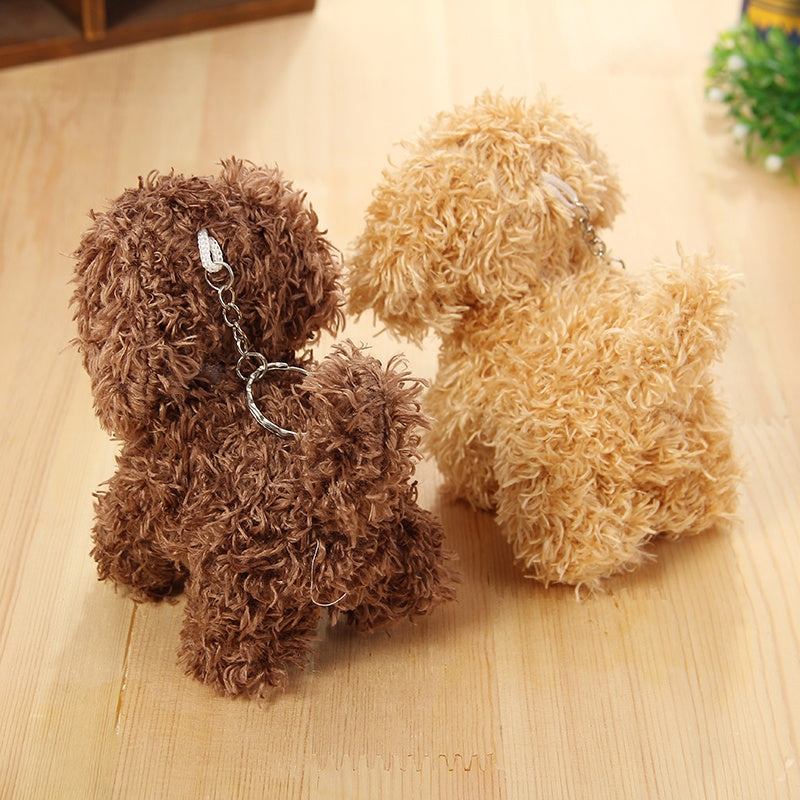Two fluffy dog-shaped keychains on a wooden surface.