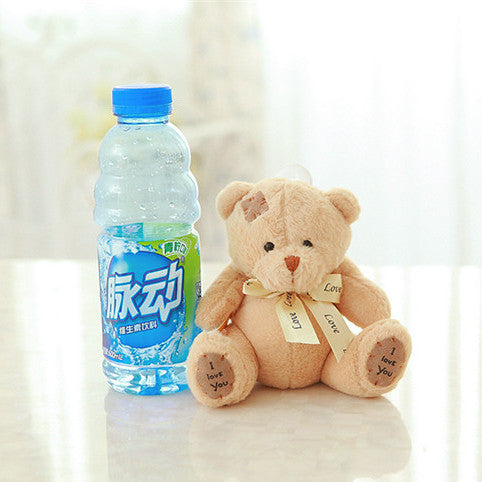 Plush teddy bear with a bottle of Moutai water on a light background.