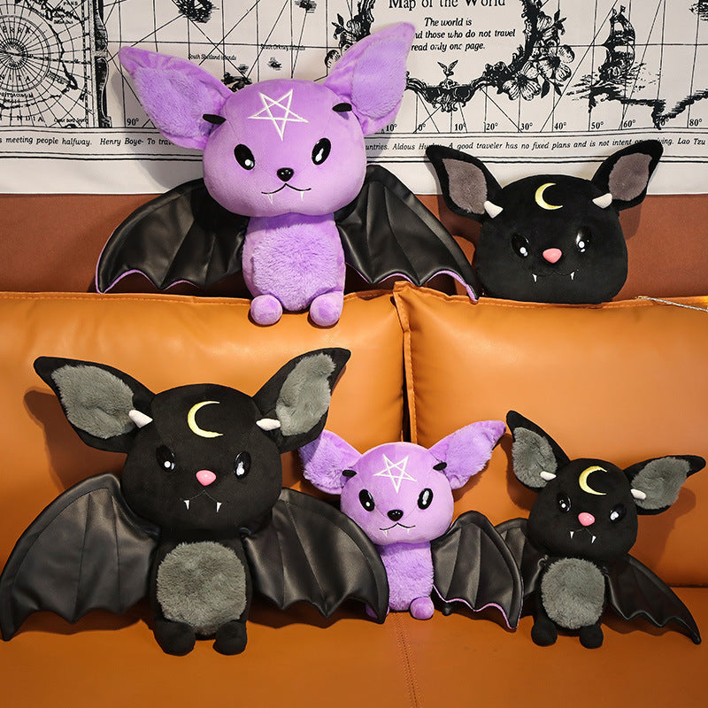 Four plush bat toys on an orange couch with a decorative wall in the background.