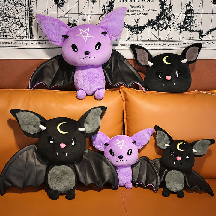 Four plush bat toys on an orange couch with a decorative wall in the background.