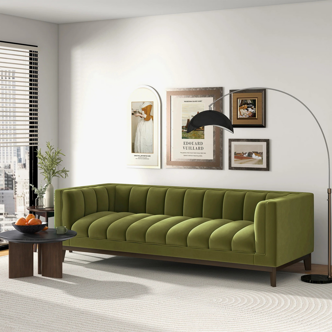 Green sofa in a living room with framed pictures on the wall.