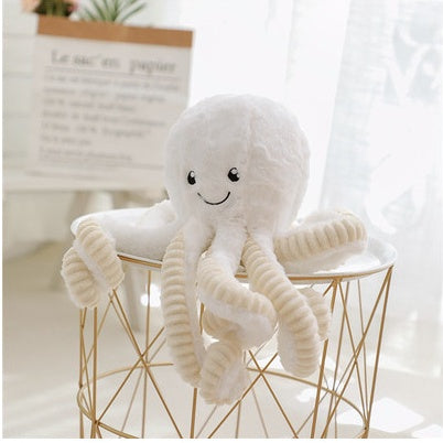 White plush octopus toy on a small round table with a light background.