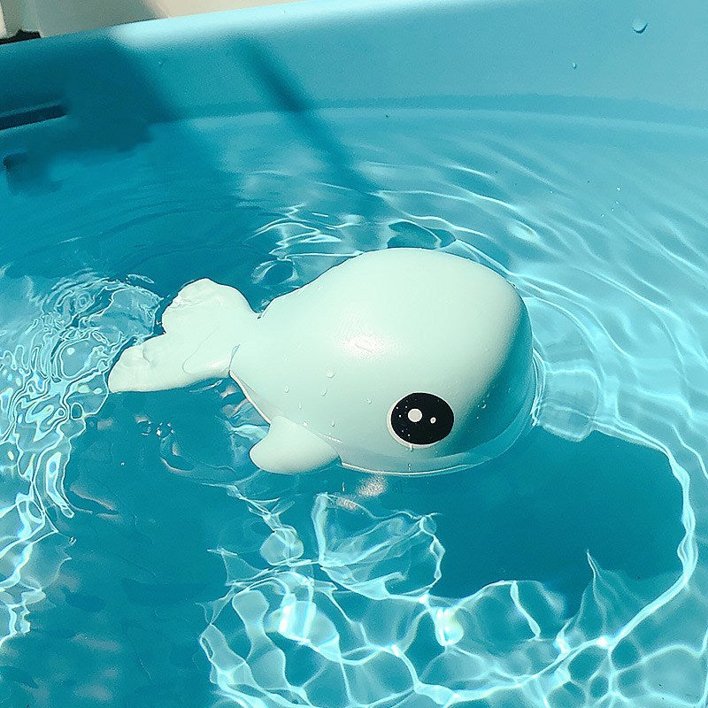Toy whale floating in clear blue water.