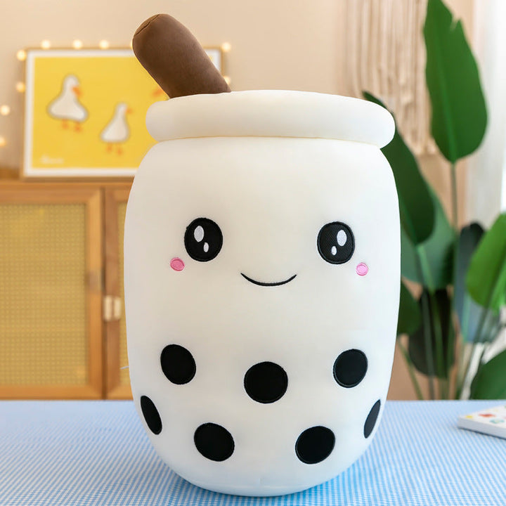 Cute plush toy resembling a bubble tea cup with a smiling face on a blue surface.