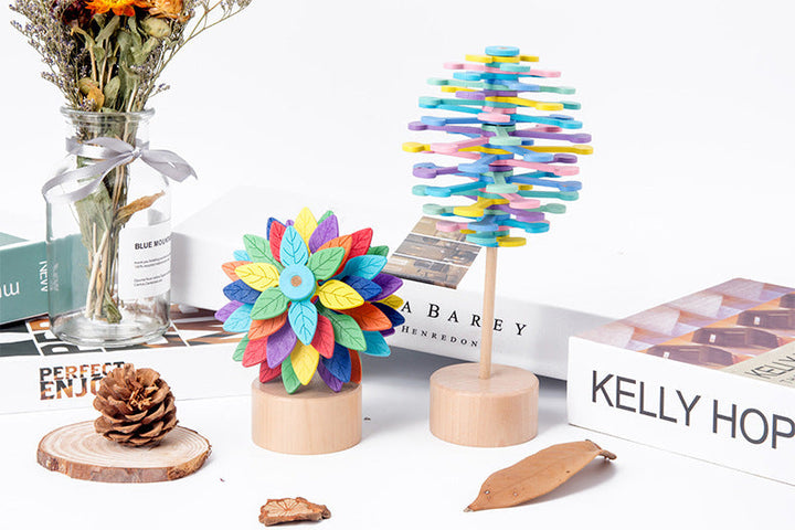 Colorful wooden toys on a white surface with books and a vase in the background.