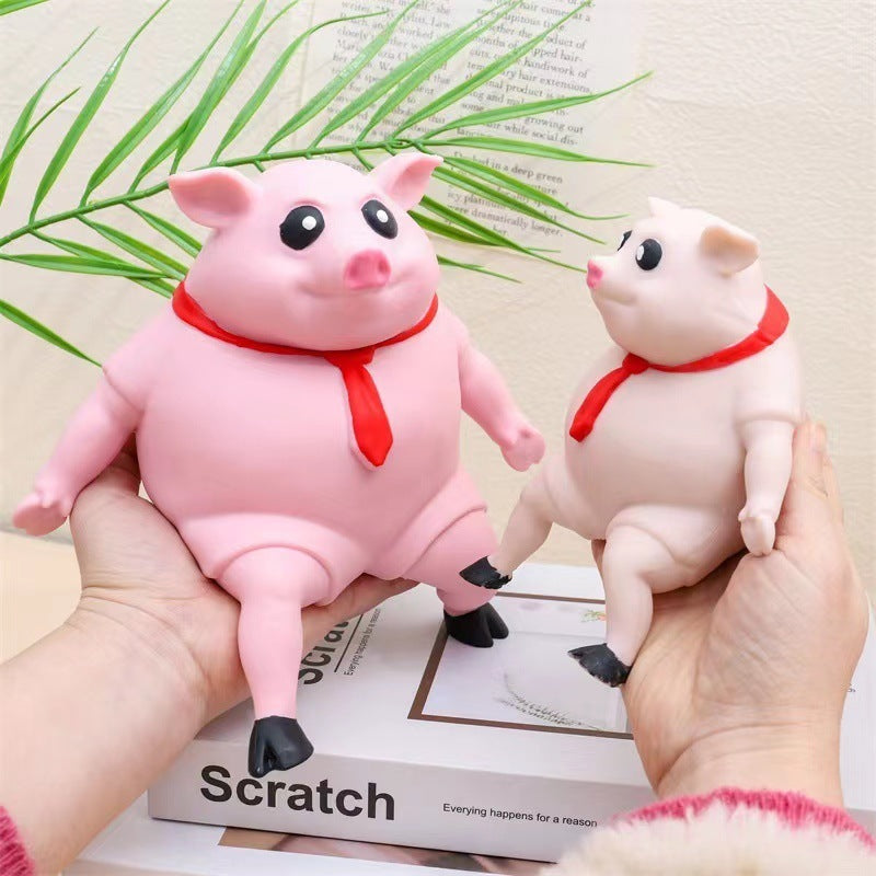 Two pink pig figurines with red scarves held by hands on a magazine background.