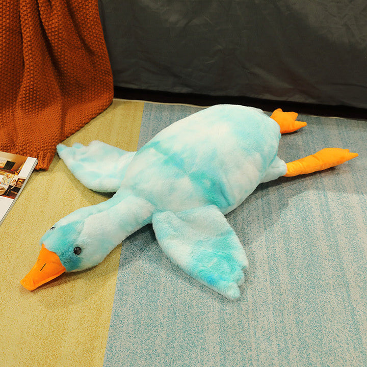 Plush toy duck on a textured surface with an orange blanket and magazine in the background.