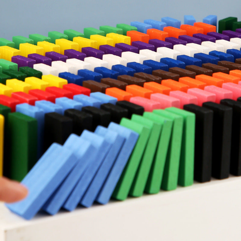 Colorful dominoes set on a light surface with a hand interacting with them.