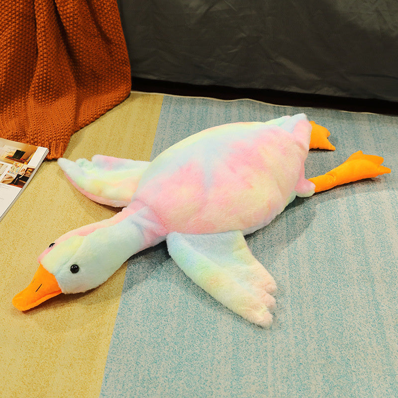 Colorful plush duck toy on a textured surface with an orange blanket and magazine in the background.