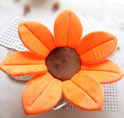 Floral-shaped cushion with orange petals on a white background.