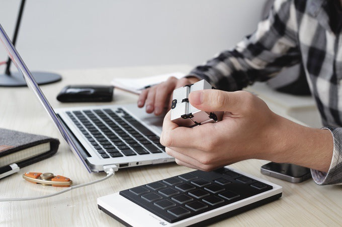 Person using a laptop with a small keyboard on a desk.