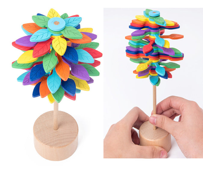 Colorful wooden tree with a base, held by a hand on a white background.