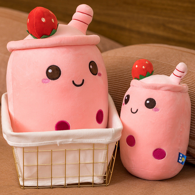 Two pink plush toys resembling milkshakes with strawberry on a brown background.