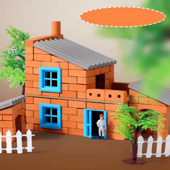 Toy house made of interlocking bricks with a small figure standing in the doorway, surrounded by greenery.