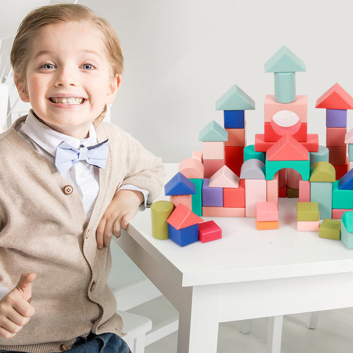 Child playing with colorful building blocks on a white table.