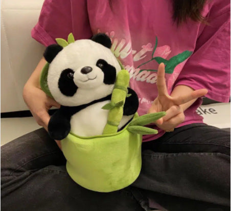 Person holding a plush panda toy with a green bamboo leaf.