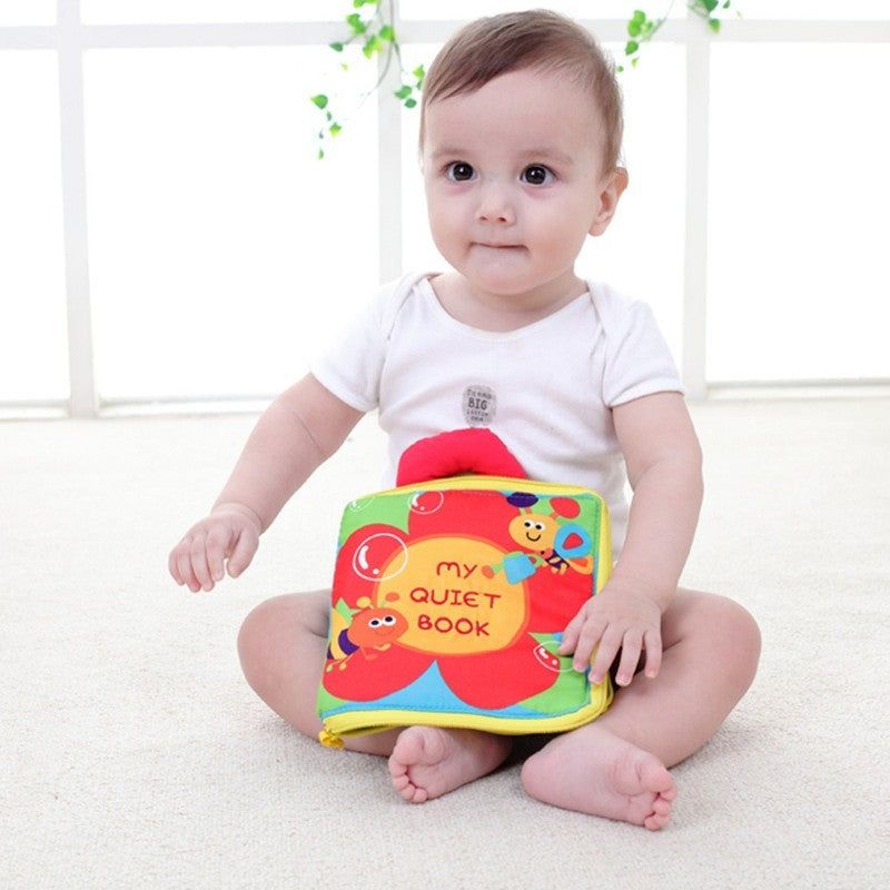 Baby holding a colorful soft book with a white background.