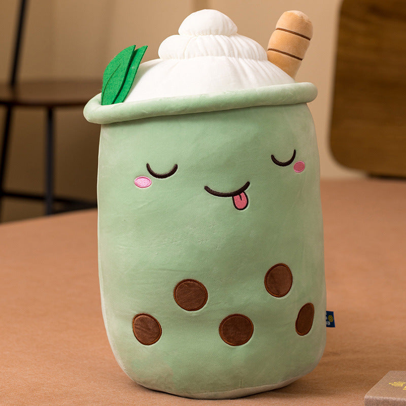 Plush toy resembling a bubble tea cup with a smiling face on a brown surface.