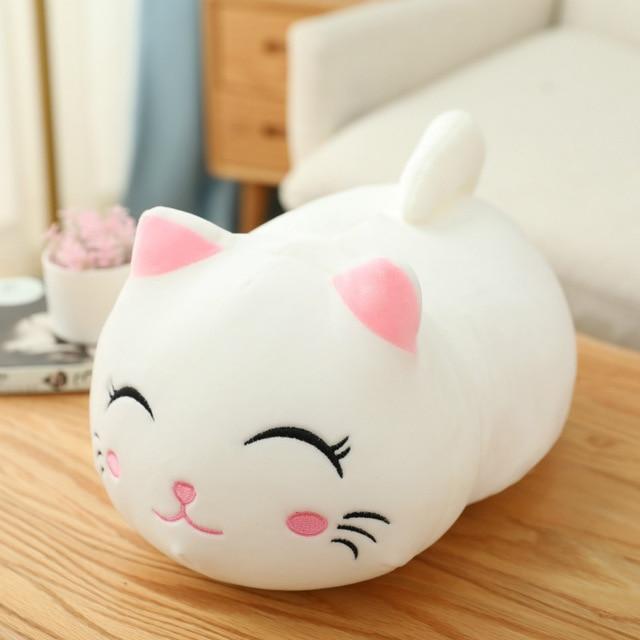 Cute white cat-shaped plush toy on a wooden surface with a blurred background.