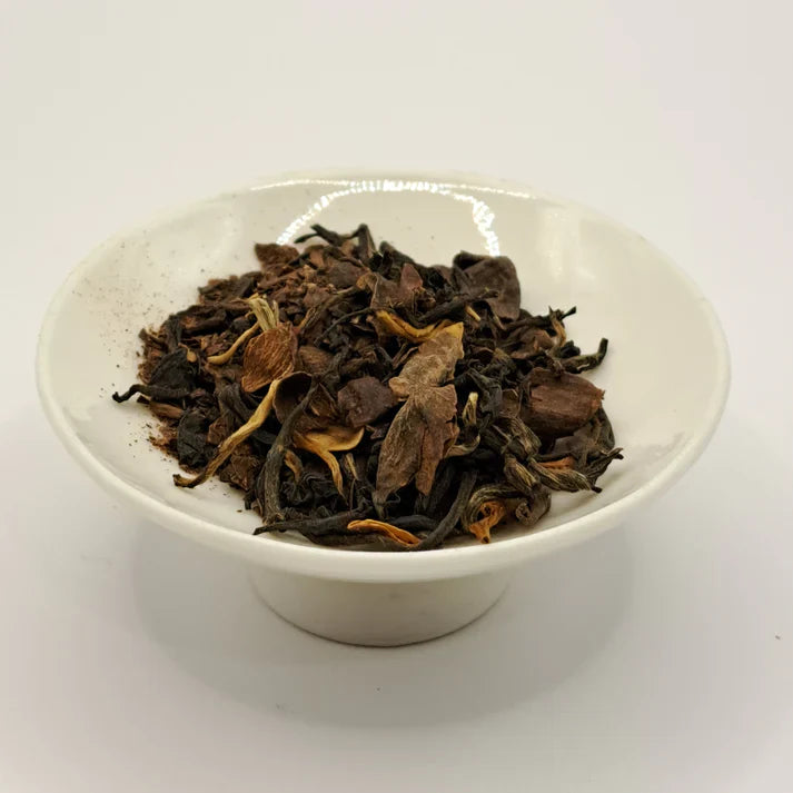 Dry tea leaves in a white bowl on a white background